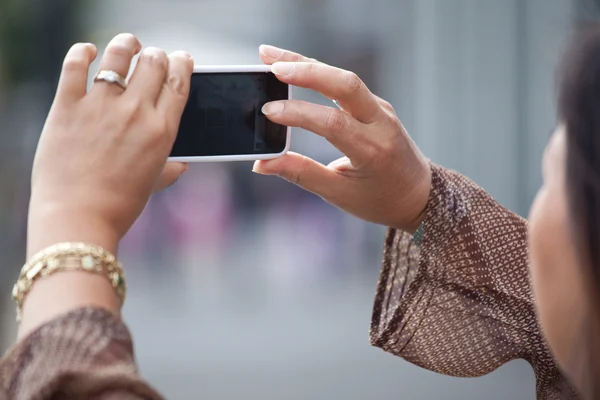Женщина-туристка фотографируется в городе со своим смартфоном  ( — стоковое фото
