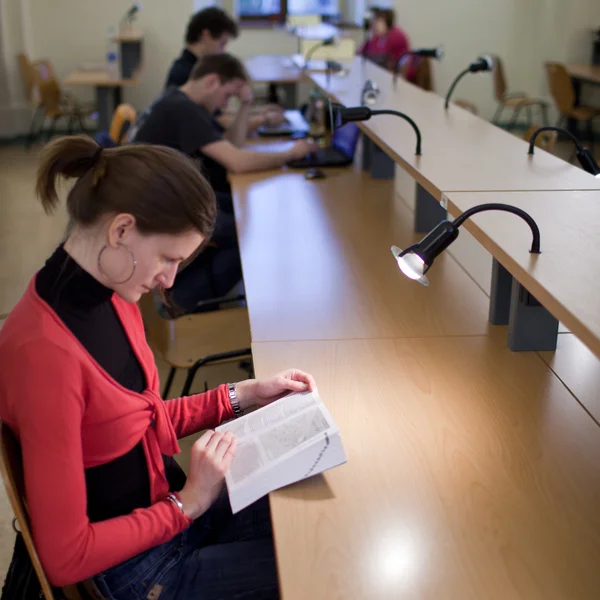 Ganska kvinnliga collegestudent i ett college bibliotek — Stockfoto
