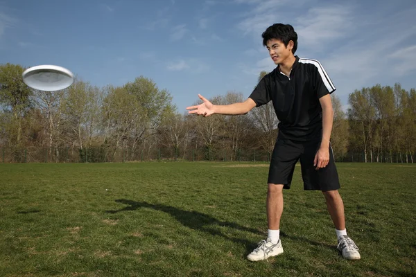Junger Mann spielt Frisbee im Park — Stockfoto
