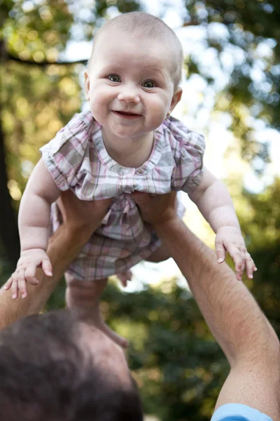 Close-up portrait of an adorable toddler in his dad's hands smil — Stock Photo, Image