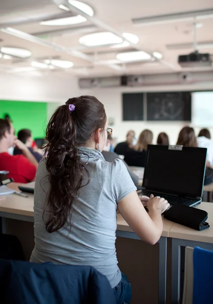 Young pretty female college student sitting in a classroom — Stock Photo, Image