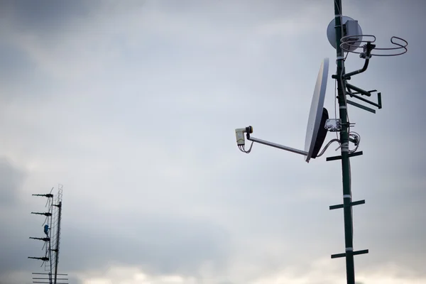 Antenler ve bir uydu çanağı bir çatı üzerinde — Stok fotoğraf
