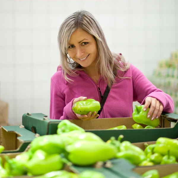 Красивая молодая женщина покупает фрукты и овощи — стоковое фото