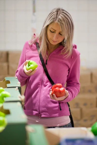Красивая молодая женщина покупает фрукты и овощи — стоковое фото