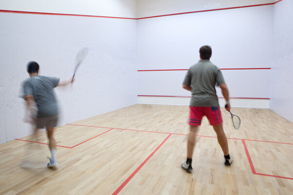 Squash players in action on a squash court (motion blurred image