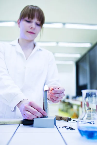 Jovem e bonita pesquisadora acendendo um queimador em um laboratório — Fotografia de Stock