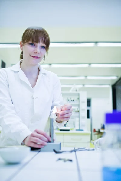 Unga och ganska kvinnliga forskare att tända upp en brännare i ett labb — Stockfoto