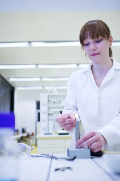 Unga och ganska kvinnliga forskare att tända upp en brännare i ett labb — Stockfoto