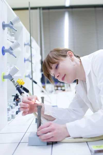 Junge und hübsche Forscherin zündet einen Brenner in einem Labor an — Stockfoto
