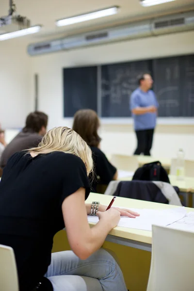 Ung ganska kvinnliga collegestudent sitter i ett klassrum — Stock fotografie