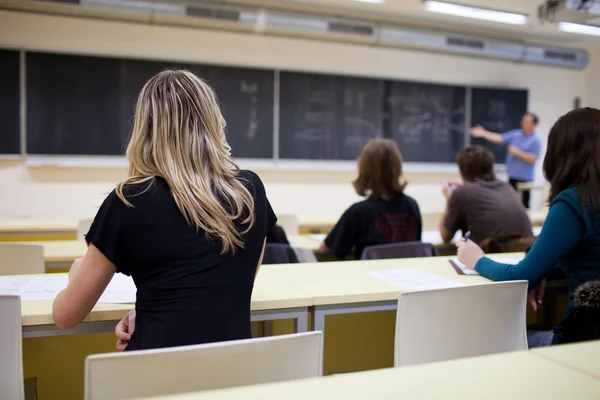 Fiatal csinos női főiskolai hallgató ül egy osztályteremben — Stock Fotó