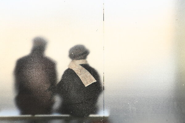 Old couple sitting in a bus stop.