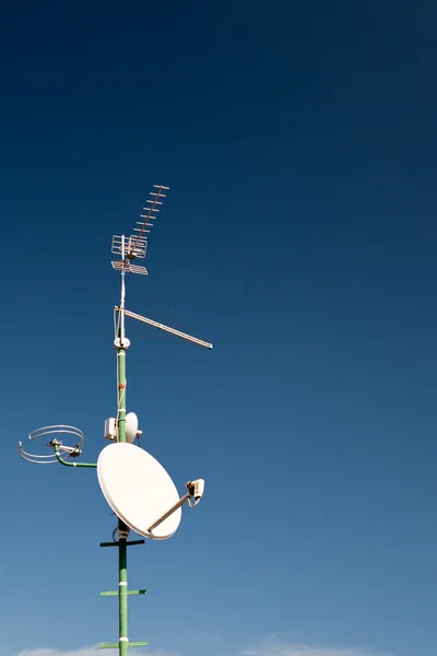 Antenner och en parabolantenn på ett tak — Stockfoto