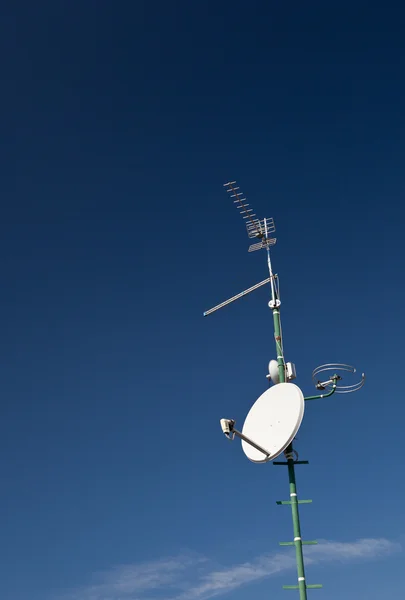 Antenas y una antena parabólica en un techo — Foto de Stock