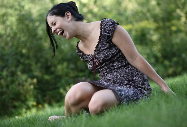 Красивая молодая женщина сидит на лужайке в парке — стоковое фото