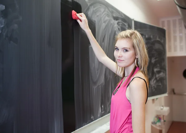 Genç ve güzel üniversite öğrencisi kara tahta/blackboard silme — Stok fotoğraf