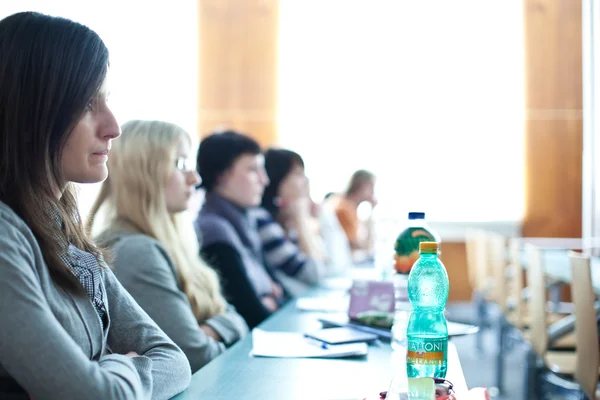 Junge hübsche College-Studentin sitzt in einem Klassenzimmer voll — Stockfoto