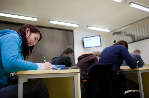 Csinos női főiskolai hallgató vizsga ül egy osztályteremben ful — Stock Fotó