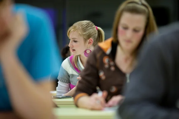 Hübsche Studentin, die in einem Klassenzimmer eine Prüfung ablegt — Stockfoto
