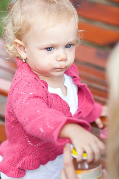 Sevimli küçük kız açık havada bir parkta elma pur besleniyor — Stok fotoğraf