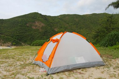 Wild camping on beach with tent clipart