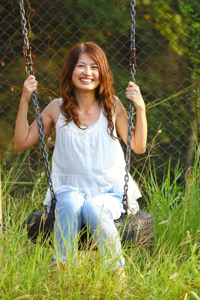 Asian girl playing swing in a park — Stock Photo, Image