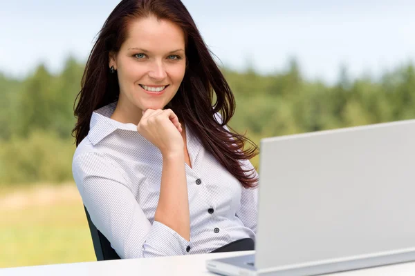 Affärskvinna i soliga natur med laptop leende — Stockfoto