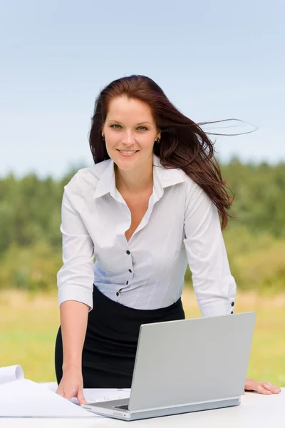 Empresária na natureza ensolarada sorrindo com laptop — Fotografia de Stock