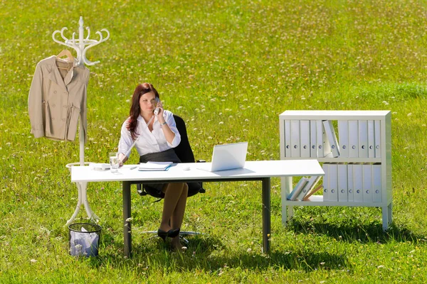 Businesswoman in sunny meadow calling nature office