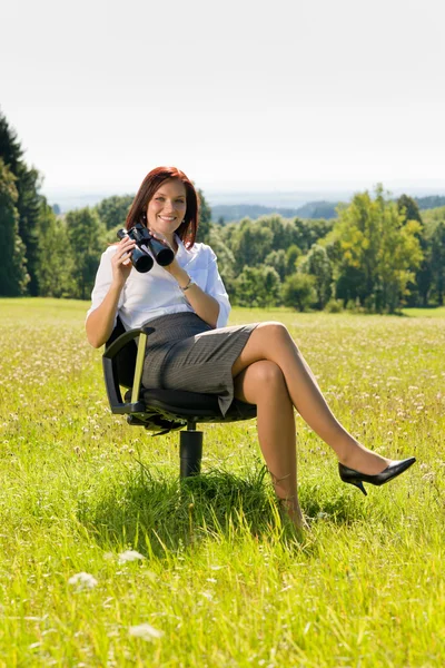 Mujer de negocios sentarse en el prado soleado buscar binocular —  Fotos de Stock