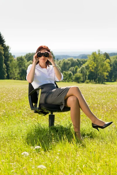 Ділова жінка сидить на сонячному лузі шукає бінокль — стокове фото