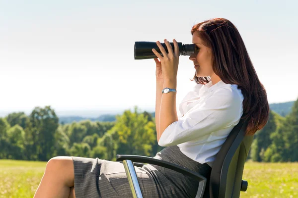 Femme d'affaires assis dans la prairie ensoleillée chercher binoculaire — Photo
