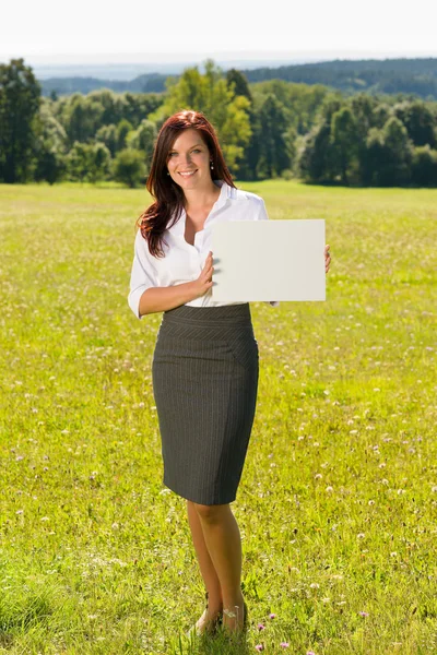 Geschäftsfrau sonnige Wiese hält leeres Transparent — Stockfoto