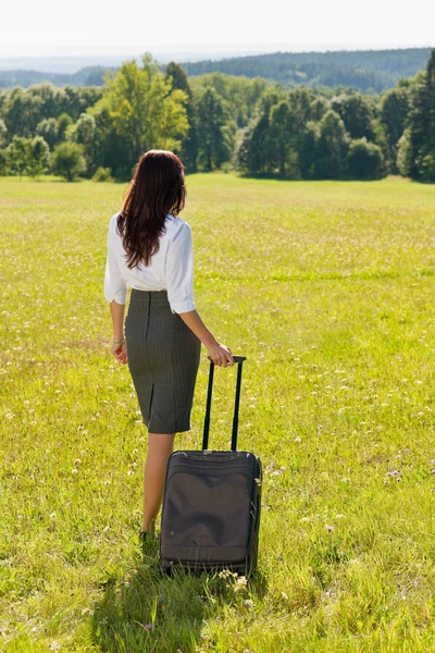 Affärskvinna solig äng lämnar med bagage — Stockfoto