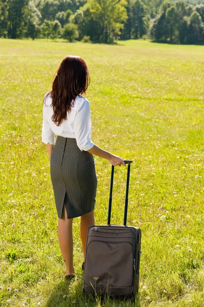 Geschäftsfrau sonnige Wiese verlässt mit Gepäck — Stockfoto