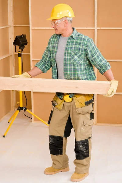 Olgun ev erkeği marangoz ahşap kiriş taşımak — Stok fotoğraf