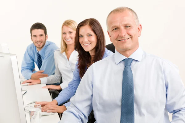 Equipe de negócios feliz sentar na fila atrás da mesa — Fotografia de Stock
