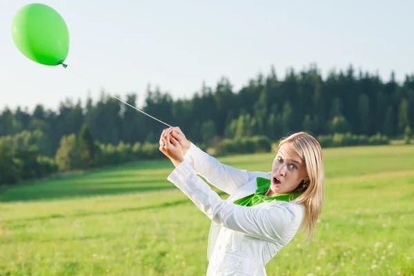 Happy young woman with green balloon meadows — Stock Photo, Image