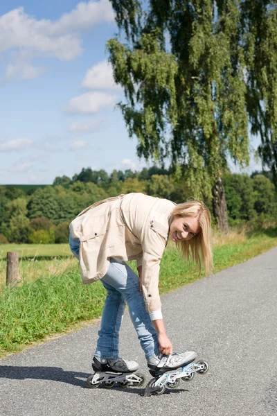 Inline skating jovem mulher na estrada de asfalto ensolarado — Fotografia de Stock