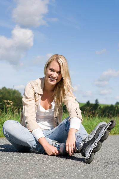 Patines en línea joven mujer sentada asfalto carretera —  Fotos de Stock