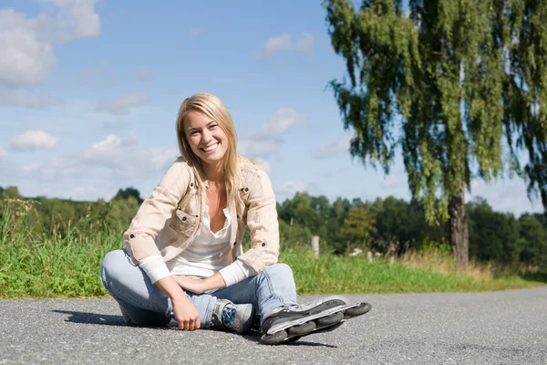 Patins à roues alignées jeune femme assise route asphaltée — Photo