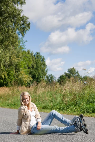 坐在沥青混凝土路面的内联溜冰鞋年轻女人 — 图库照片