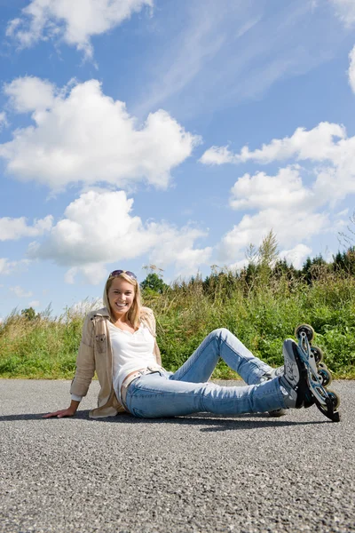 Pattini in linea giovane donna seduta strada asfaltata — Foto Stock