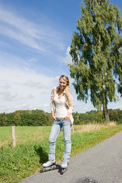 Inline skating young woman on sunny asphalt road — Stock Photo, Image