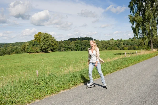 日当たりの良いアスファルトの道路にインライン スケートの若い女性 — ストック写真