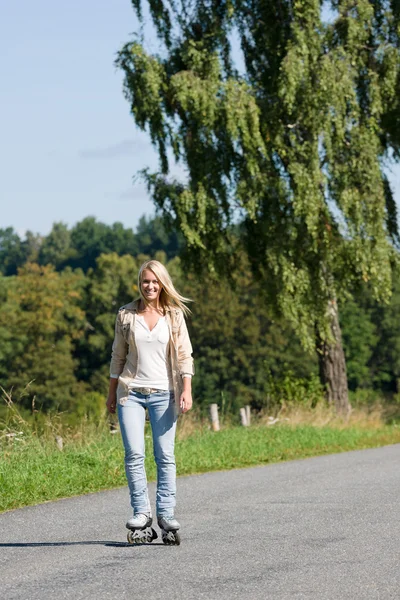 Конькобежная молодая женщина на солнечной асфальтовой дороге — стоковое фото