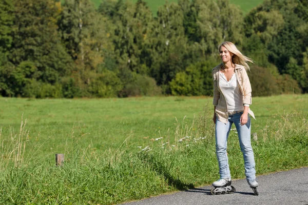 Patinaje en línea mujer joven en camino asfaltado soleado —  Fotos de Stock