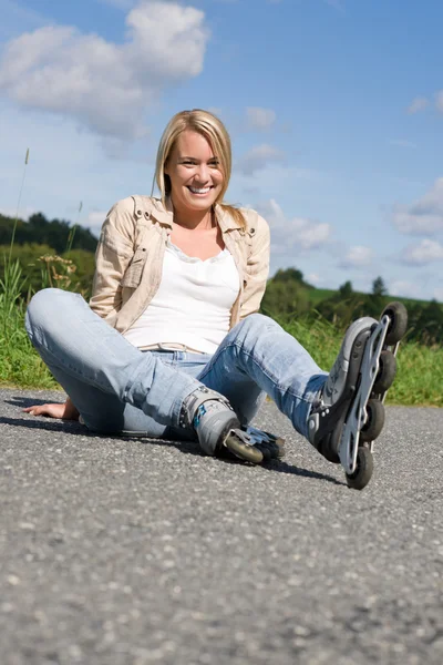 Patines en línea joven mujer sentada asfalto carretera — Foto de Stock