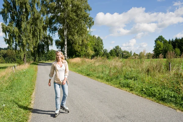 Patinage en ligne jeune femme sur route asphaltée ensoleillée — Photo