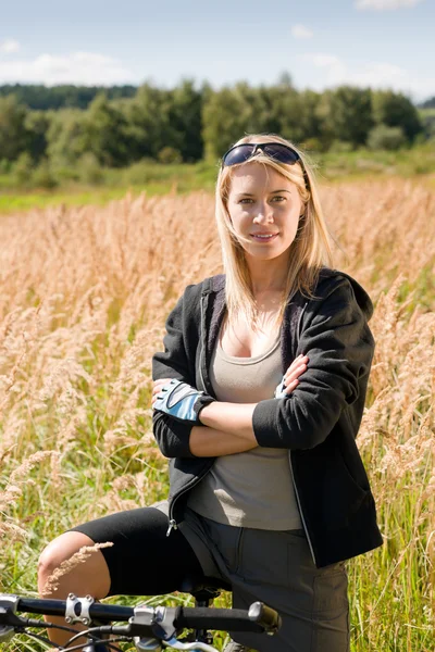 マウンテン バイクの若い女性の陽気な日当たりの良い牧草地 — ストック写真